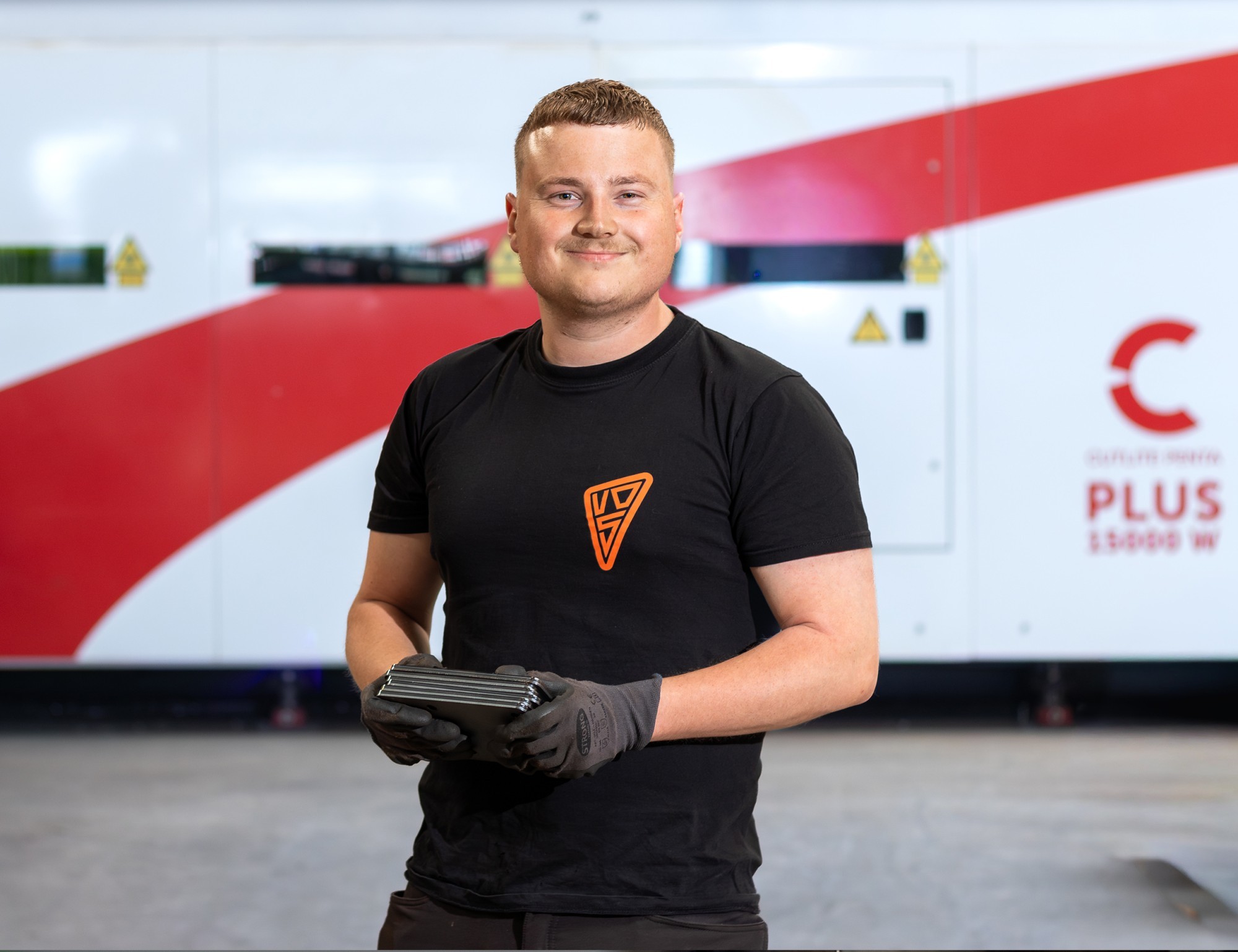 Werknemer toont metalen platen in een productieomgeving bij een Lasersnijmachine